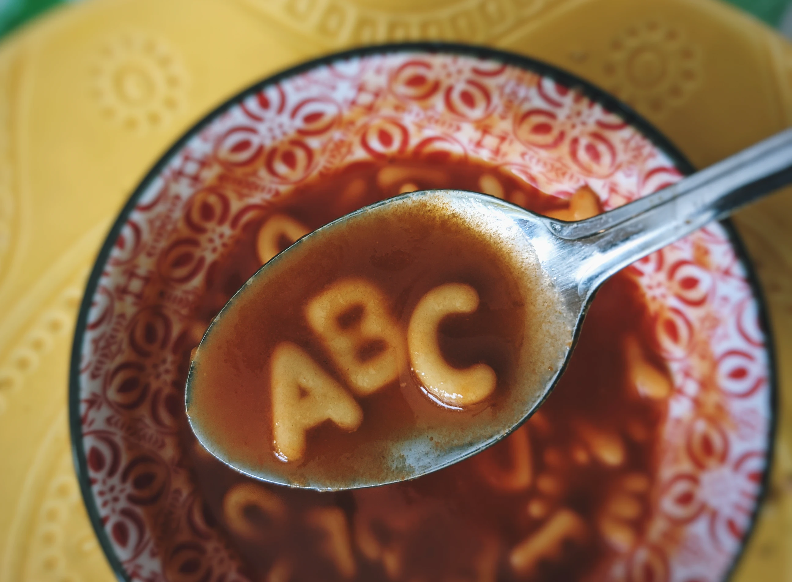 Bowl of soup with a spoon on it, with the letters ABC.