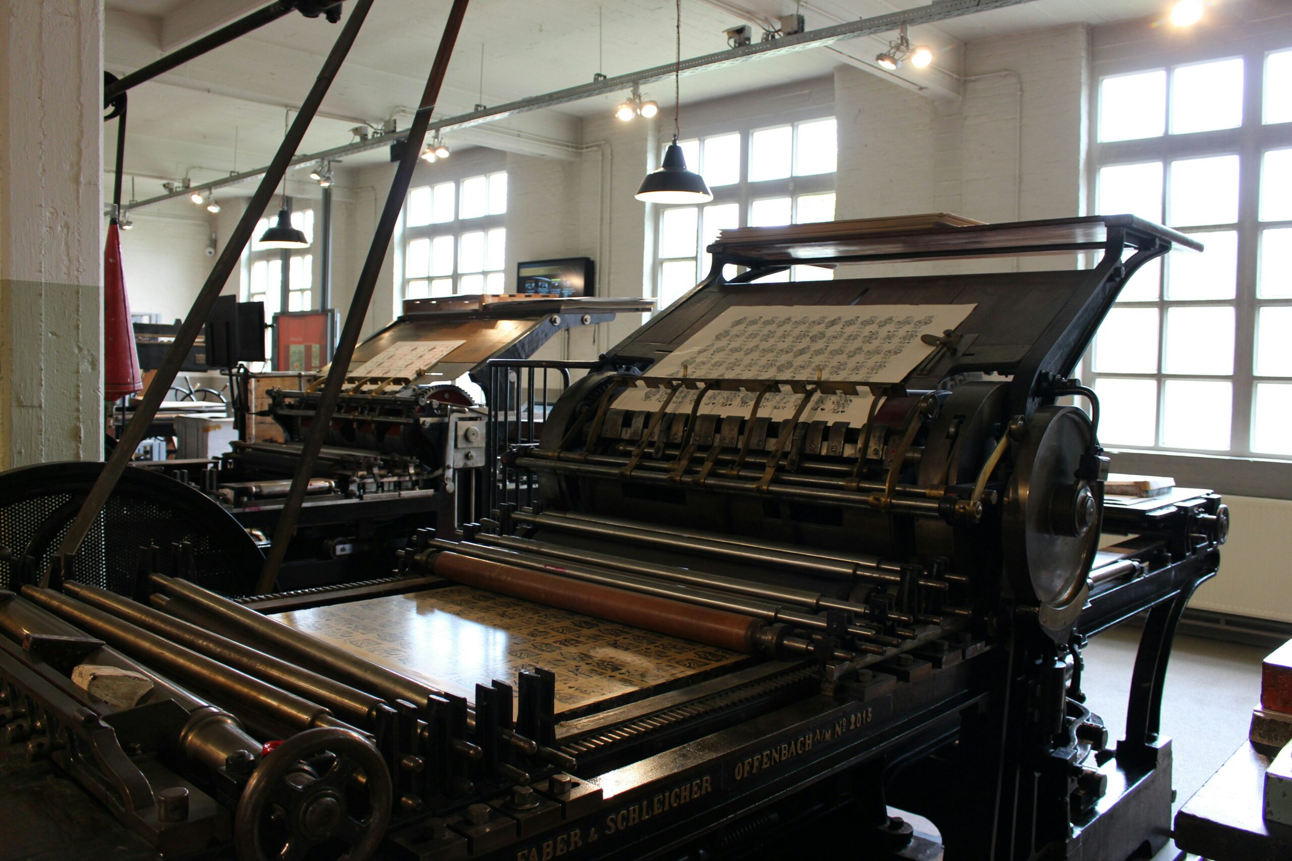 Two printing presses producing material.