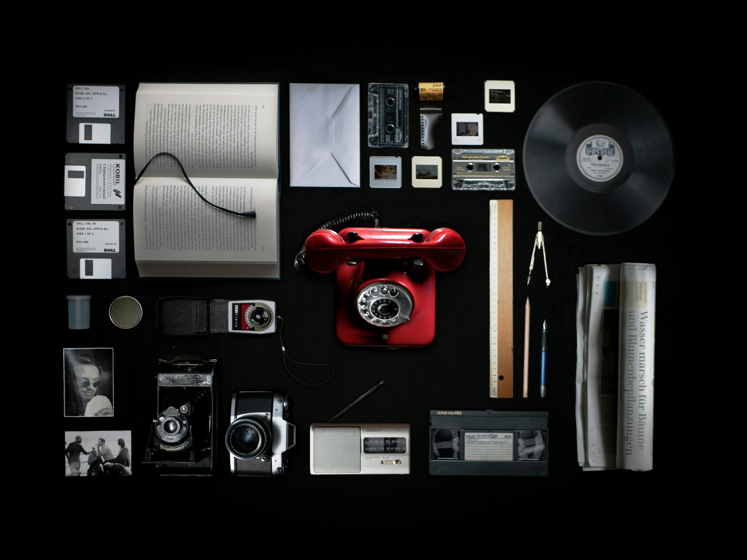 A rectangular collage of physical mediums. A red rotary phone is in the center.