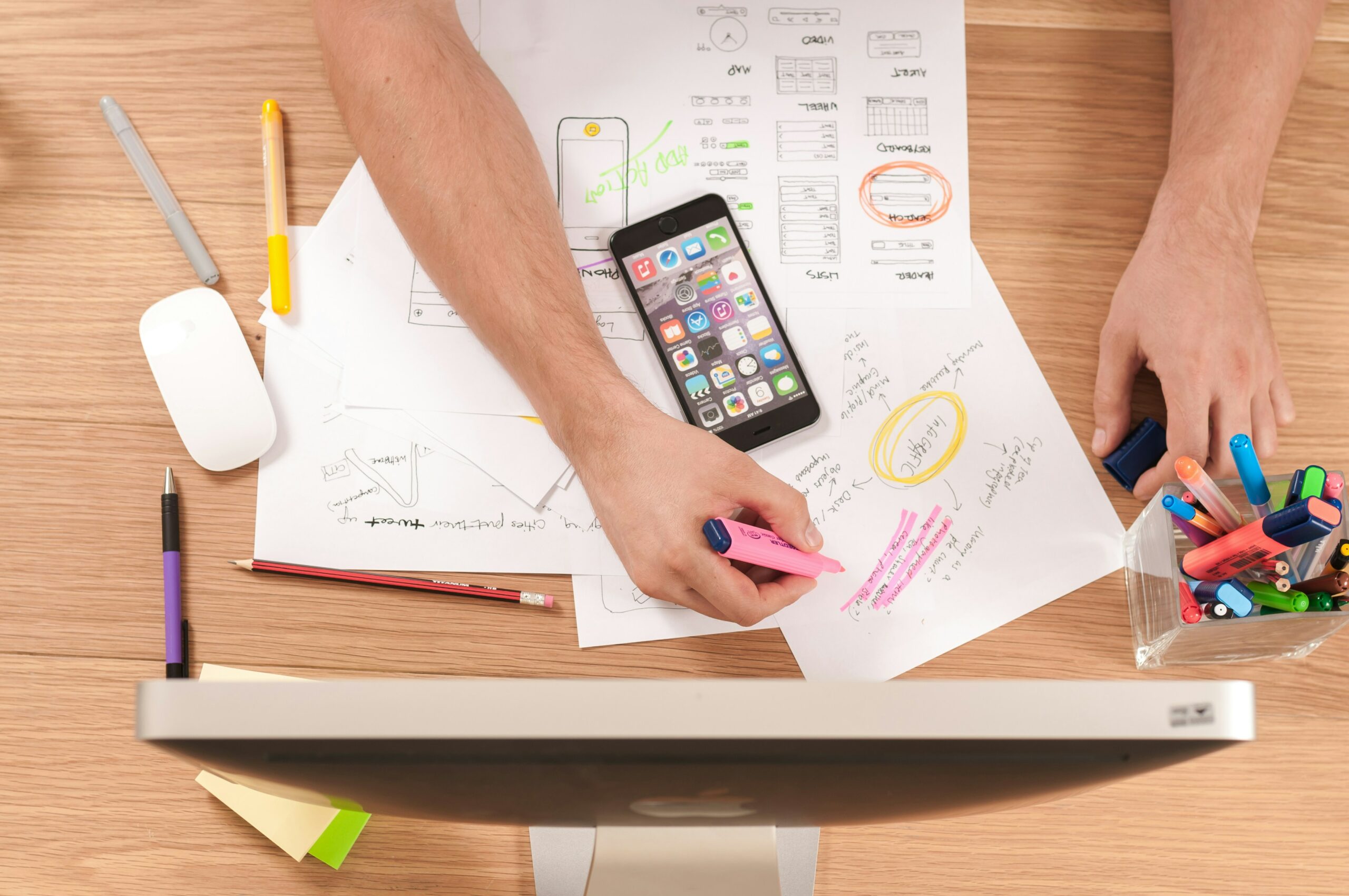 Person highlighting something on a piece of paper, with an unlocked Iphone resting on the paper