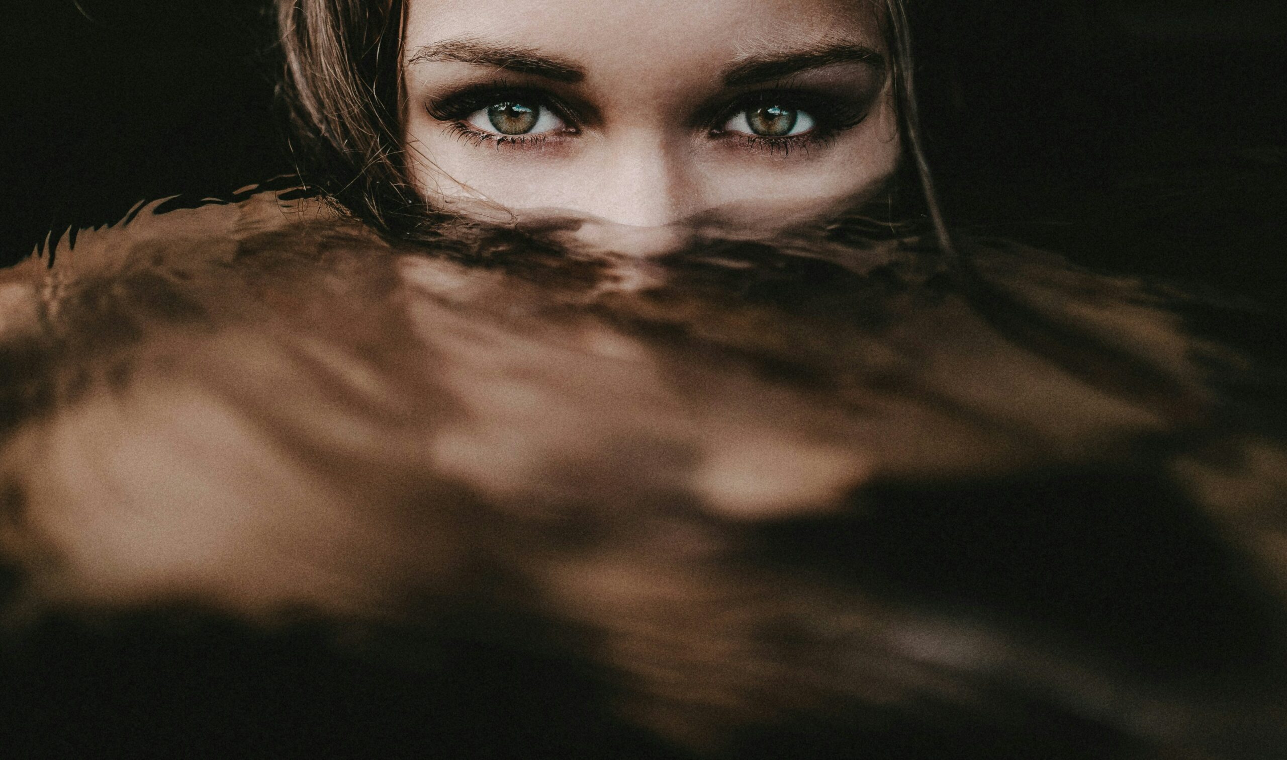 A girl with her green eyes, just above the surface of water. Her eyes are what she uses for visual rhetoric.