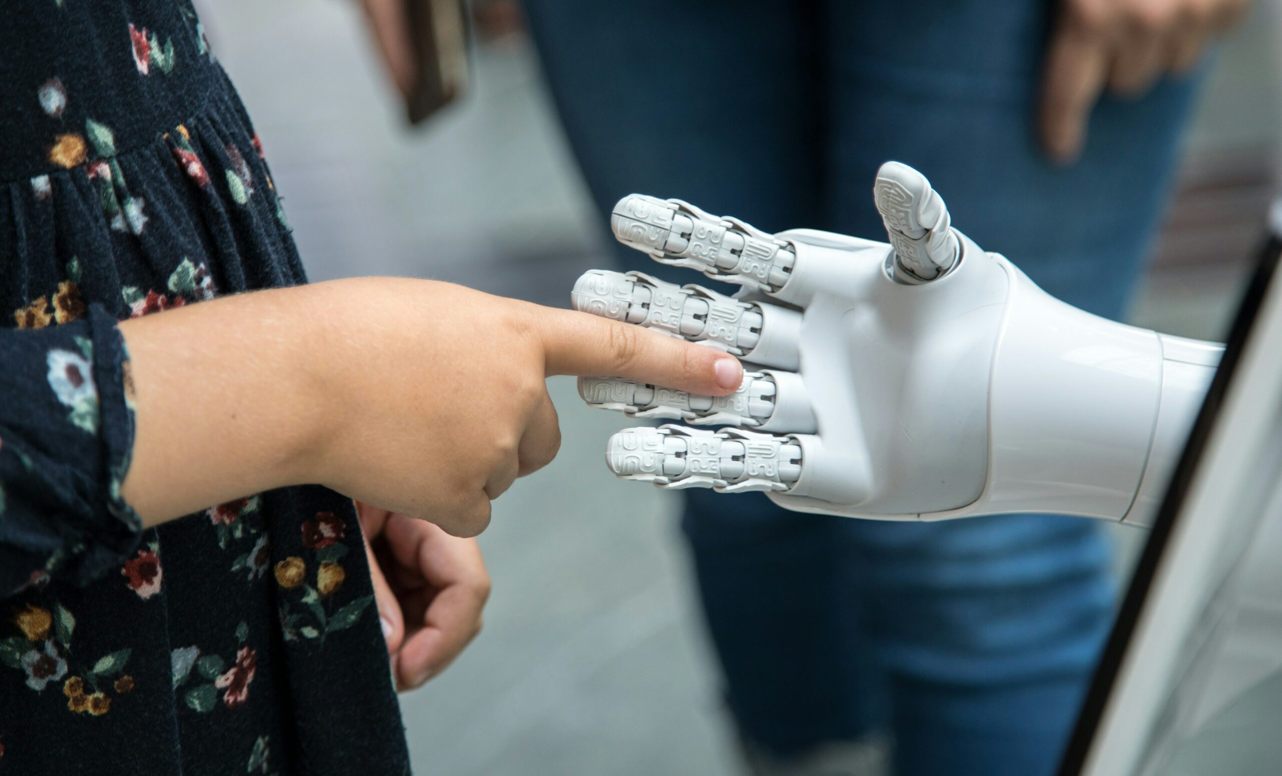 A human hand holding out its pointer finger to touch a robot hand.
