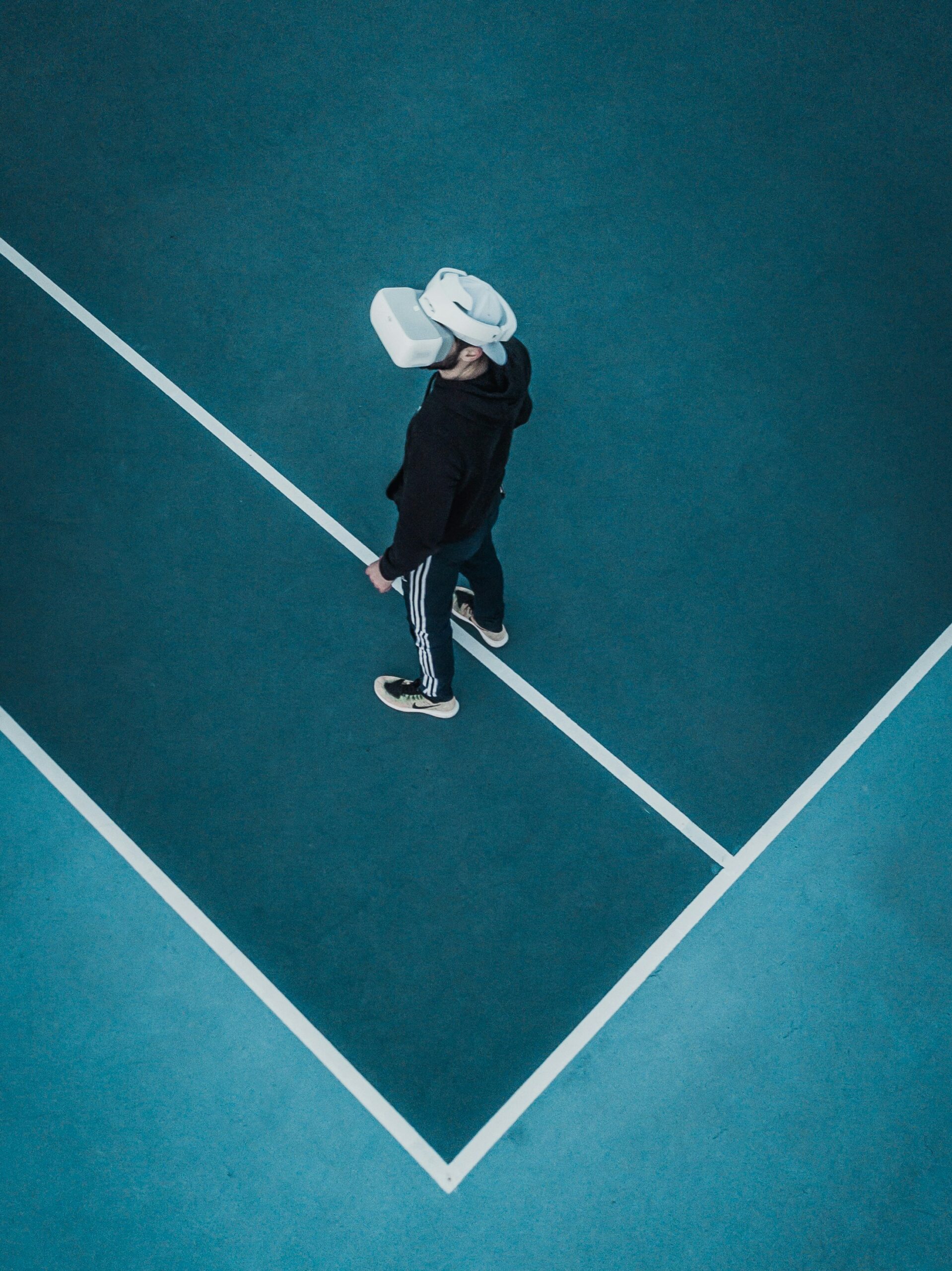 Man wearing VR headset while standing on a tennis court.