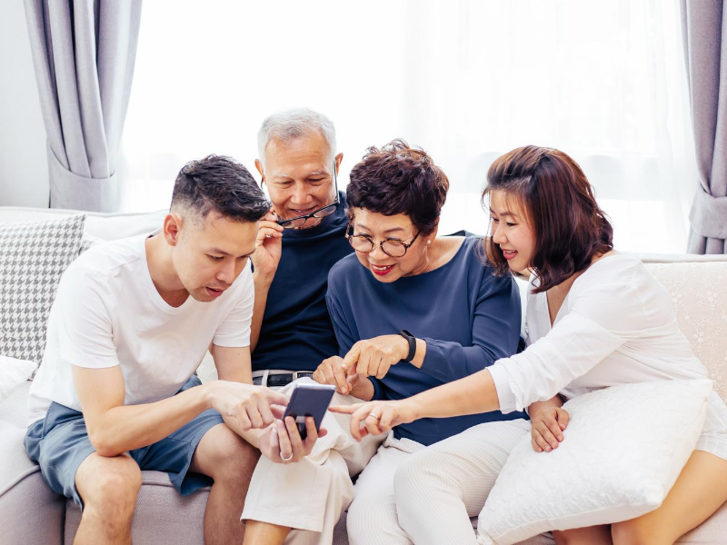 Younger generation showing older generation how to use a phone.
