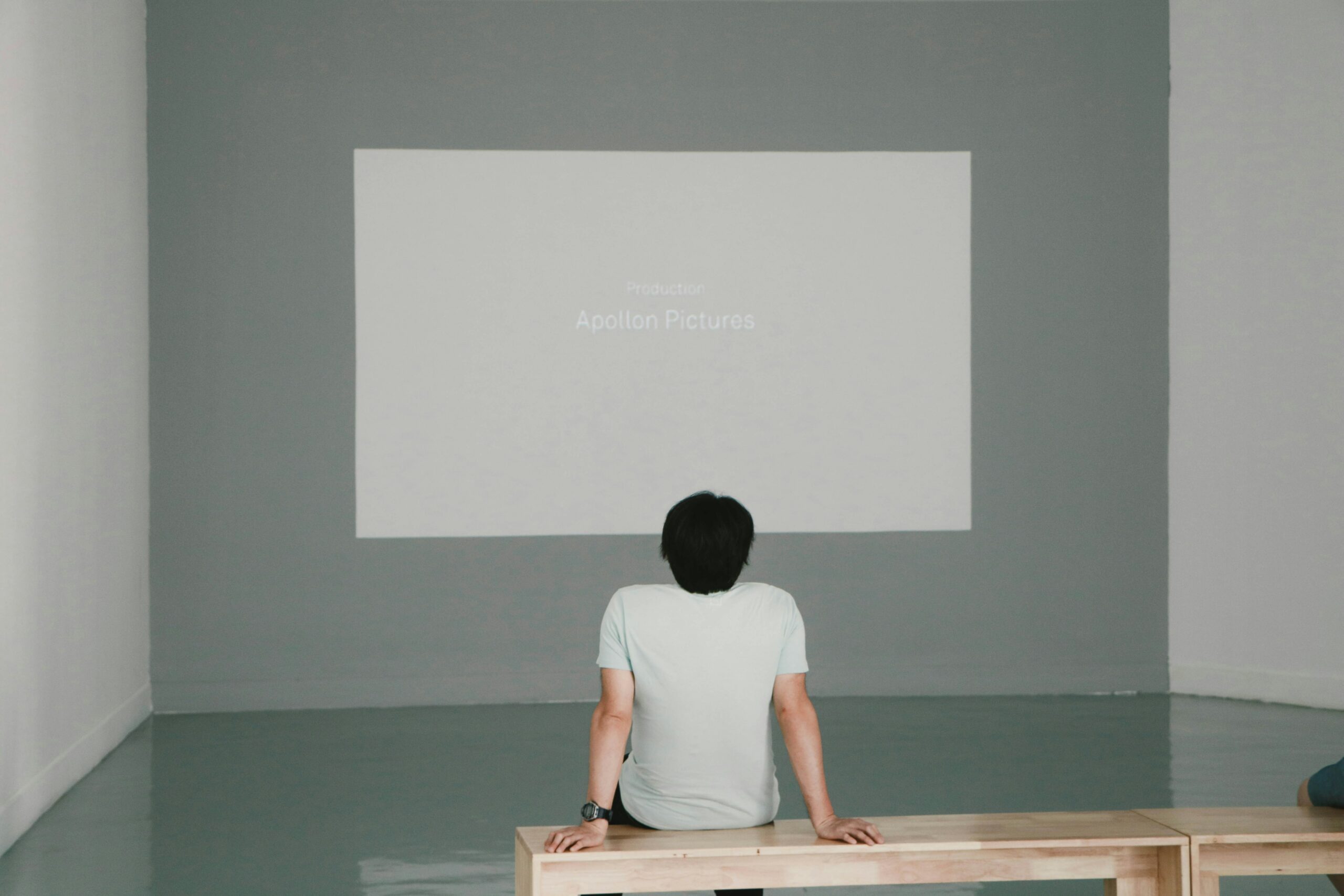 A person sits in front of a white screen with fading text.