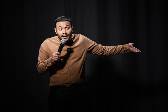 A man delivers a stand-up set, thus engaging in new media.