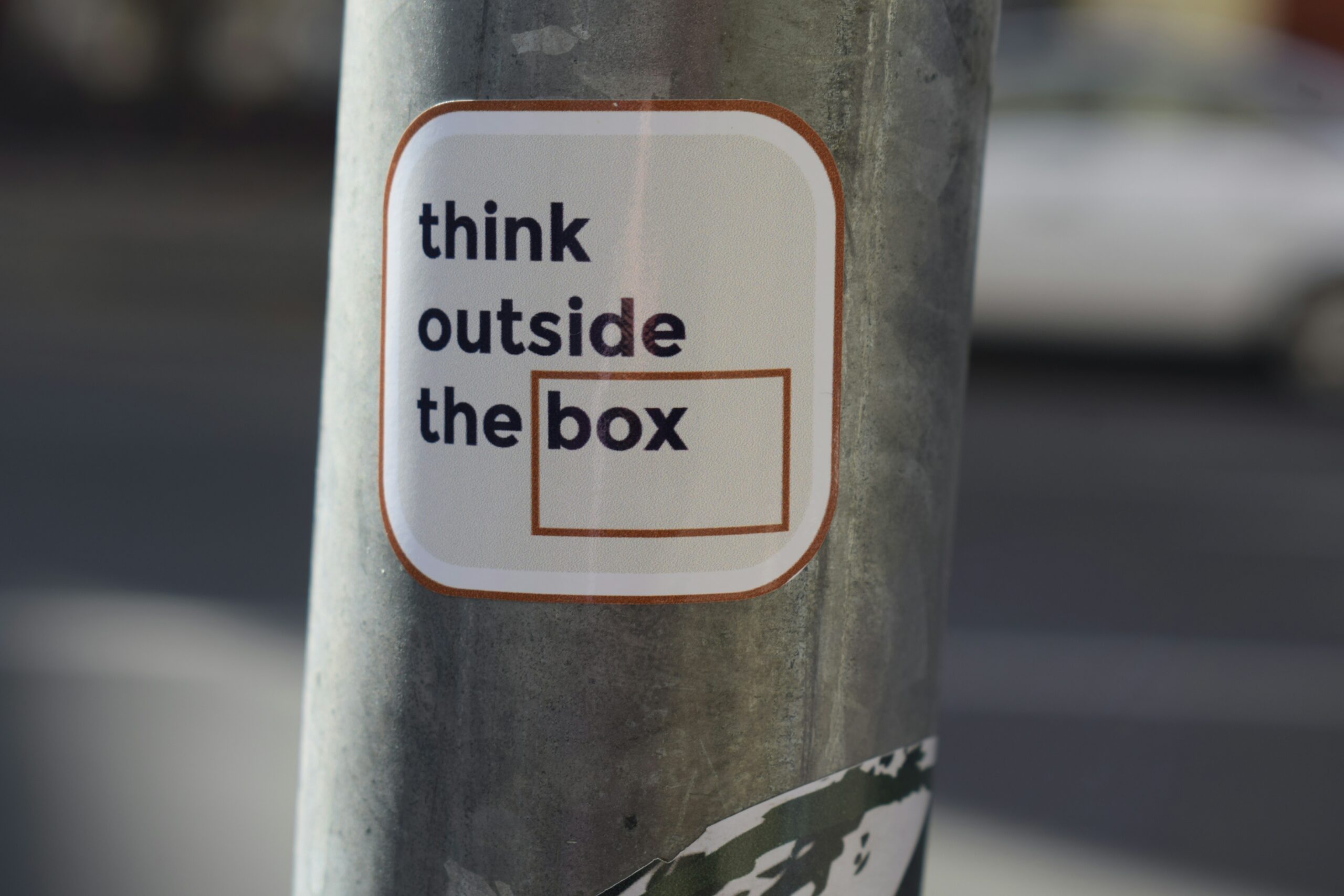 A sign posted on a pole saying "Think outside the box"