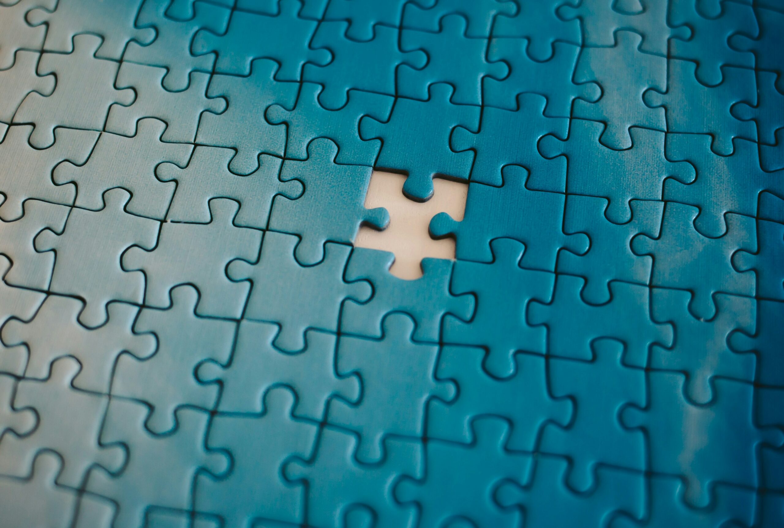 A group of connected blue puzzle pieces that are missing a piece in the center where the person connecting them together is using intertextuality to get the next part of the whole.