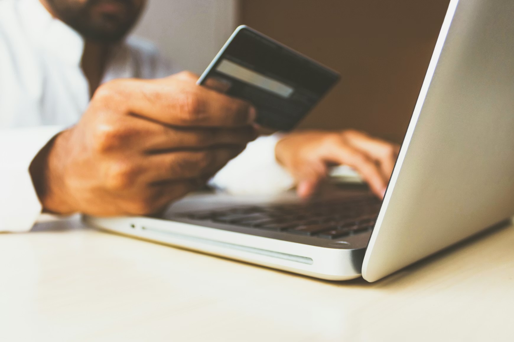 Individual has laptop open and a credit card in hand, making online purchase.